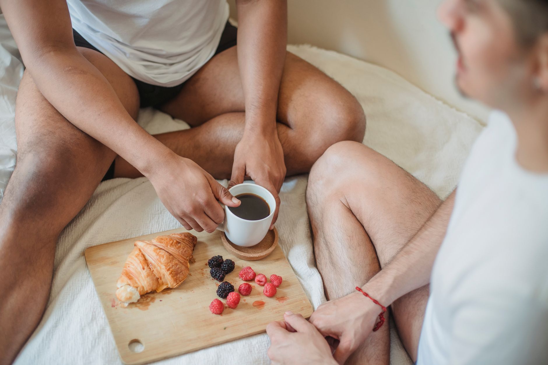 Guests sharing breakfast in robes on a hotel bed